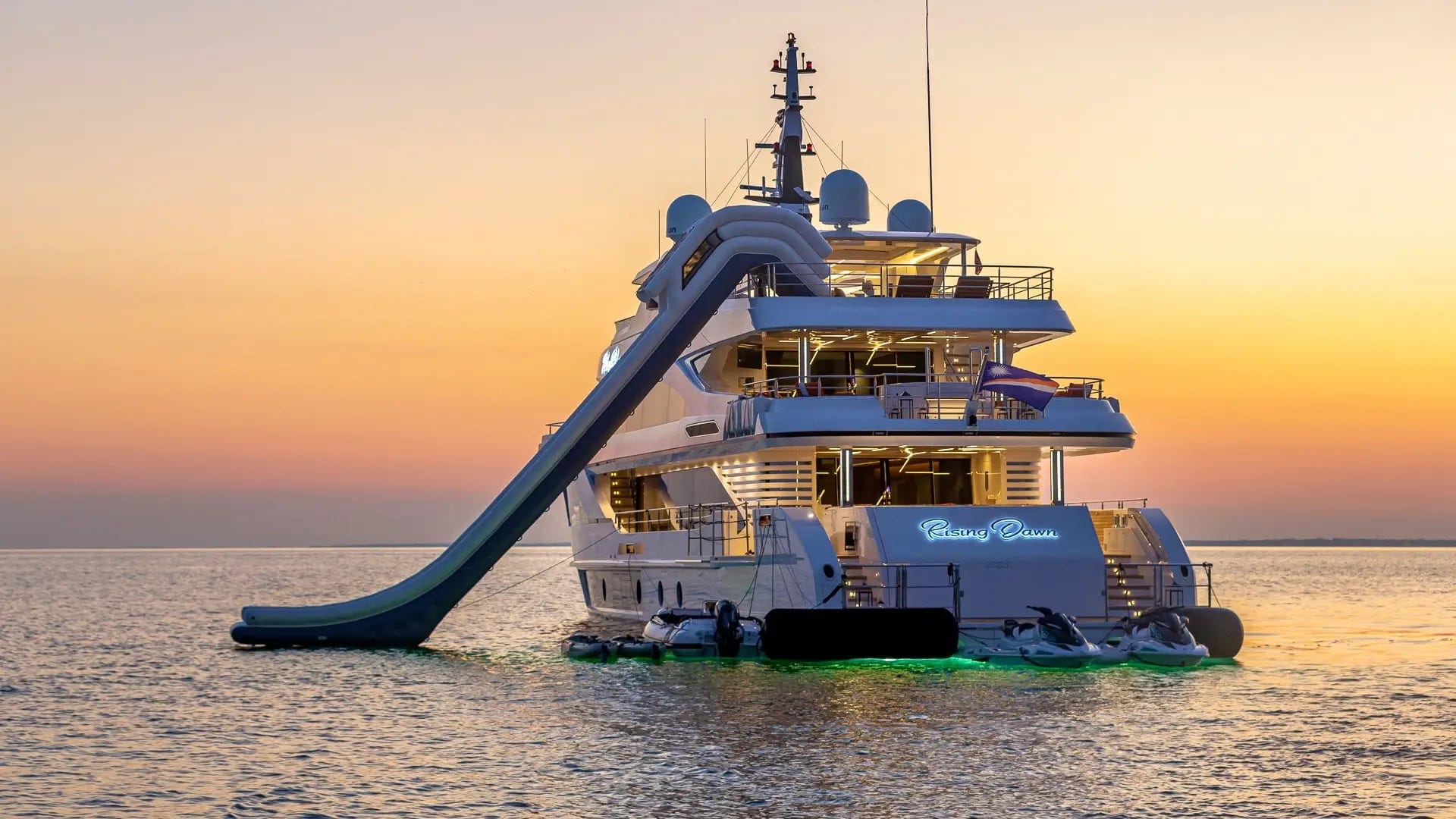 A motor yacht at anchor at sunset with her water slide out